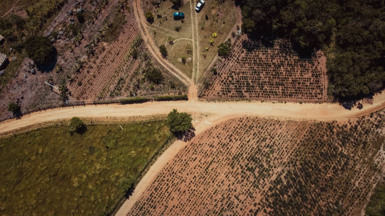 Vista aérea de estradas de terra e áreas agrícolas entre campos rurais em Tubarão, Santa Catarina.