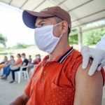Homem recebe vacina em uma clínica de atendimento ao ar livre.